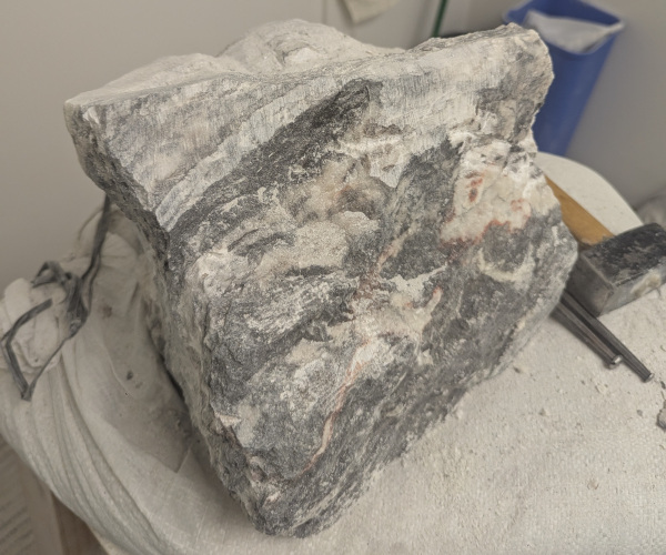 a sculpture depicting a head being held by a hand with brains oozing out of it