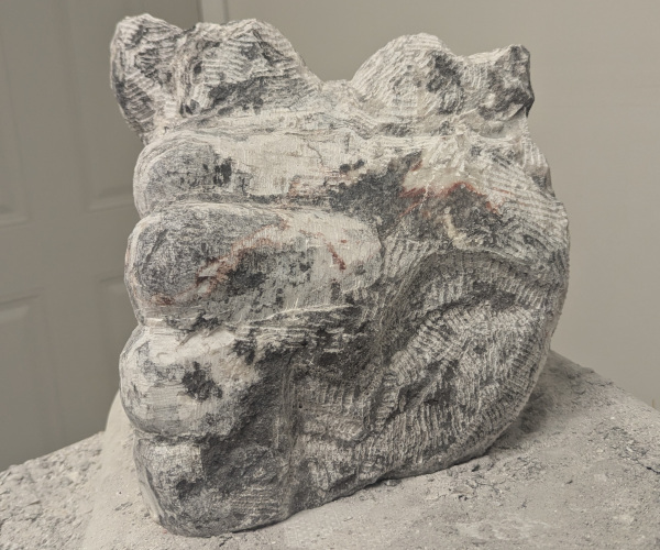 a sculpture depicting a head being held by a hand with brains oozing out of it