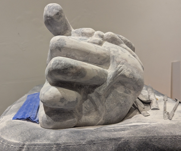 a sculpture depicting a head being held by a hand with brains oozing out of it