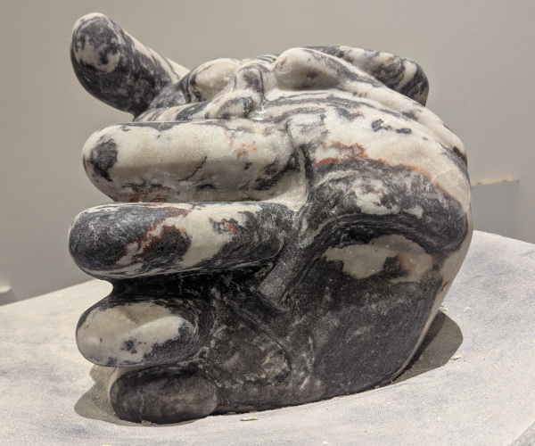 a sculpture depicting a head being held by a hand with brains oozing out of it